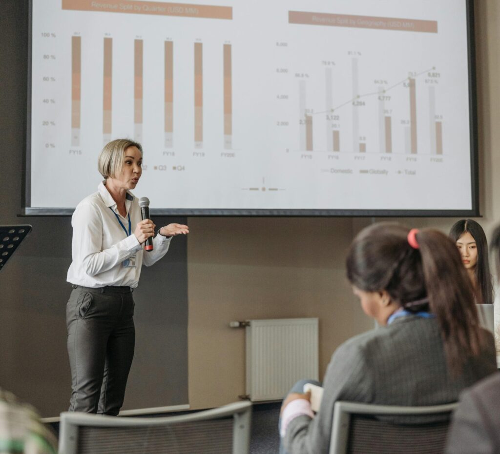 pexels-photo-8761528-8761528 A professional woman leads a seminar on revenue analysis, engaging participants with graphs and data.